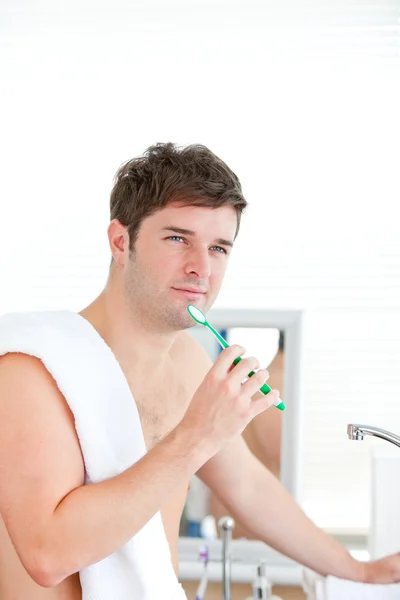 Задуманный человек чистит зуб полотенцем на плече. — стоковое фото