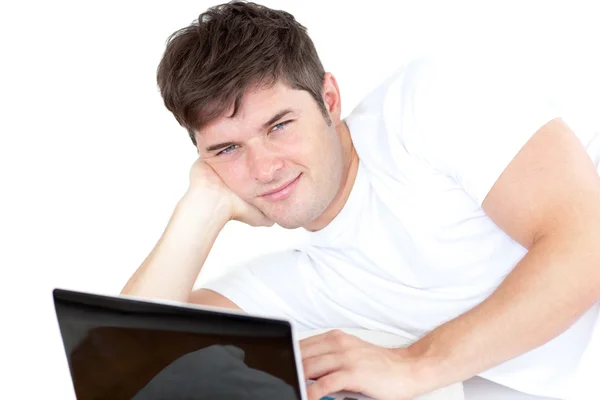 Привабливий молодий чоловік, використовуючи свій комп'ютер, лежить на підлозі — стокове фото