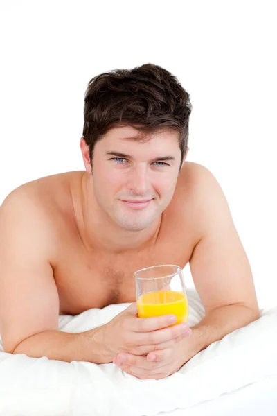 Hombre de pecho desnudo acostado en su cama con un vaso de jugo de naranja — Foto de Stock
