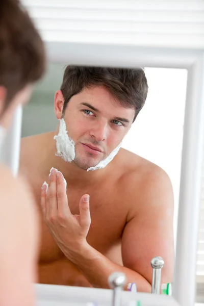 Młody człowiek wprowadzenie niektórych pianki do golenia, szuka jego twarz w mirr — Zdjęcie stockowe