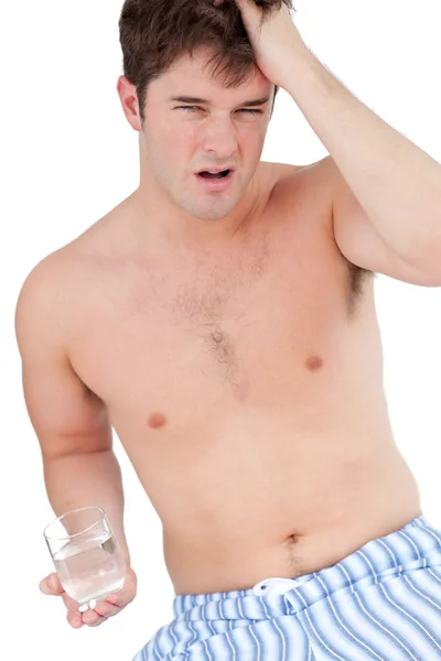 Człowiek w piżamy, trzymając szklankę wody patrząc wyczerpany — Zdjęcie stockowe