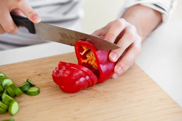 Primer plano de un hombre cortando pimiento rojo de pie en la cocina — Foto de Stock