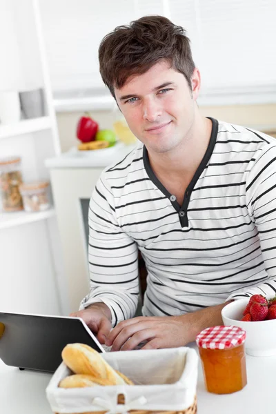 Joven usando su portátil durante su desayuno sentado en el k — Foto de Stock