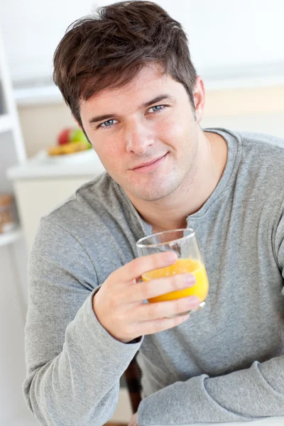 Atrakcyjny młody człowiek picie soku pomarańczowego w kuchni — Zdjęcie stockowe