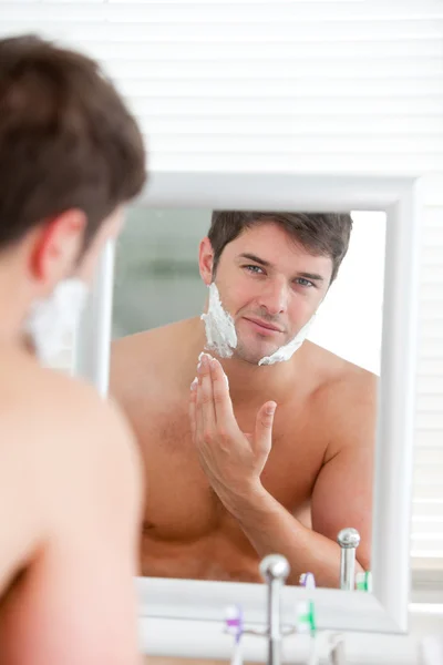 Młody człowiek wprowadzenie niektórych pianki do golenia, stoi w łazience — Zdjęcie stockowe