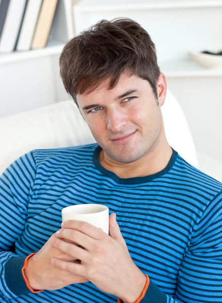 Glücklicher Mann auf dem Sofa liegend mit einer Tasse Tee im Wohnzimmer — Stockfoto