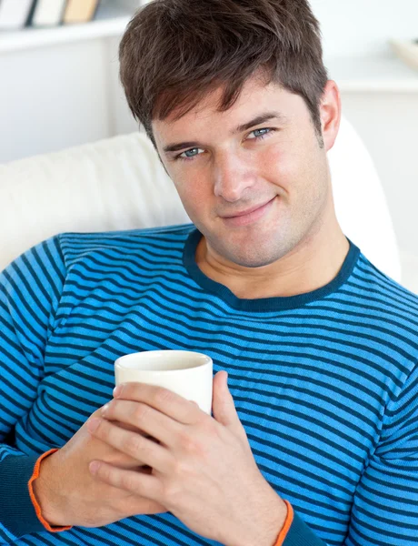 Šťastný muž, spočívající na jeho pohovce s šálkem kávy — Stock fotografie