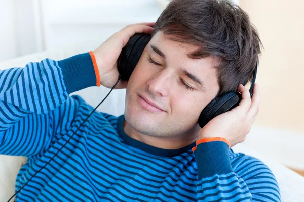 Fredlig man lyssnar musik håller sitt öronsnäckorna liggande på den — Stockfoto