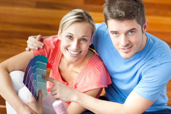 Bright couple choosing colour for their new house sitting in the — Stock Photo, Image
