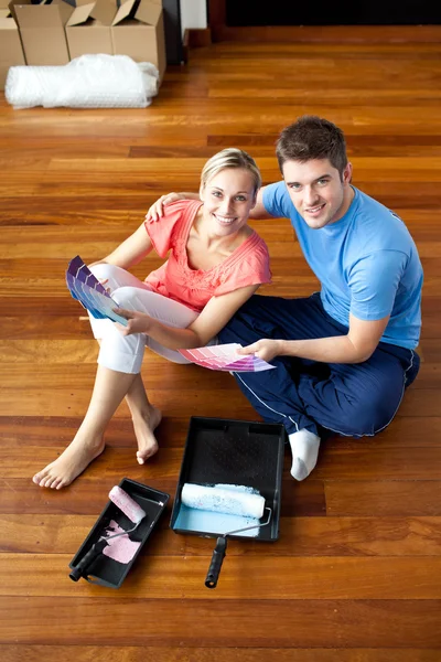 Beautiful couple sits on the floor picking colors — Stock Photo, Image