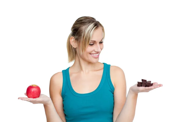 Young woman comparing apple with chocolate — Stock Photo, Image