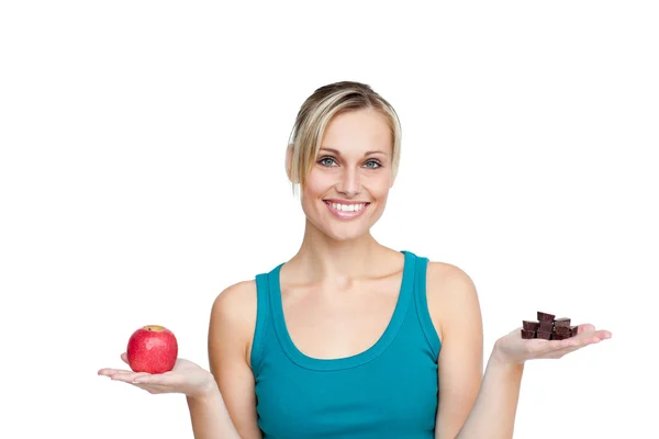 Beautifull woman comparing apple with chocolates — Stock Photo, Image