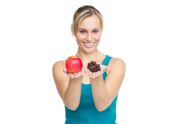 Caucasian woman holding an apple and chocolates — Stock Photo, Image