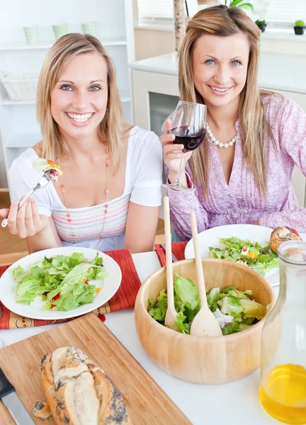 Duas amigas positivas comendo salada na cozinha — Fotografia de Stock