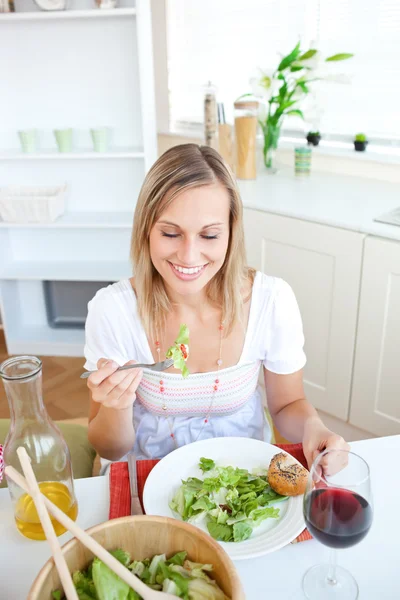 Söt kvinna äta sallad i köket — Stockfoto