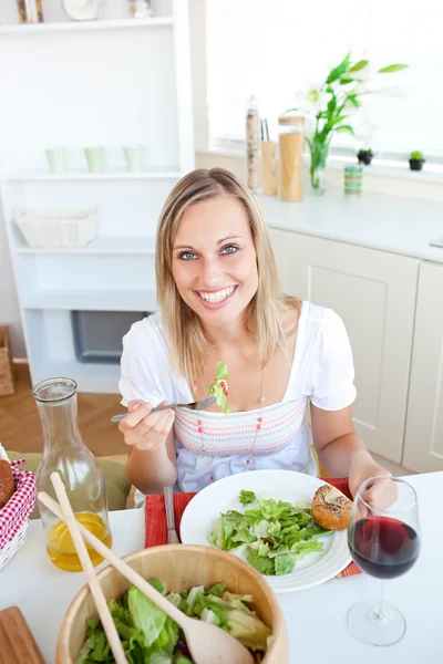 Mujer sonriente comiendo ensalada en la cocina —  Fotos de Stock