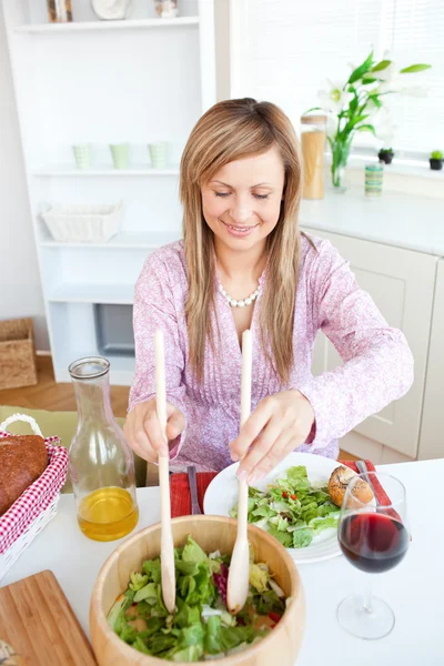Сияющая женщина ест салат на кухне — стоковое фото