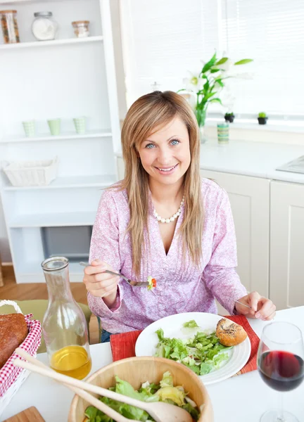 美しい女性が台所でサラダを食べる — ストック写真