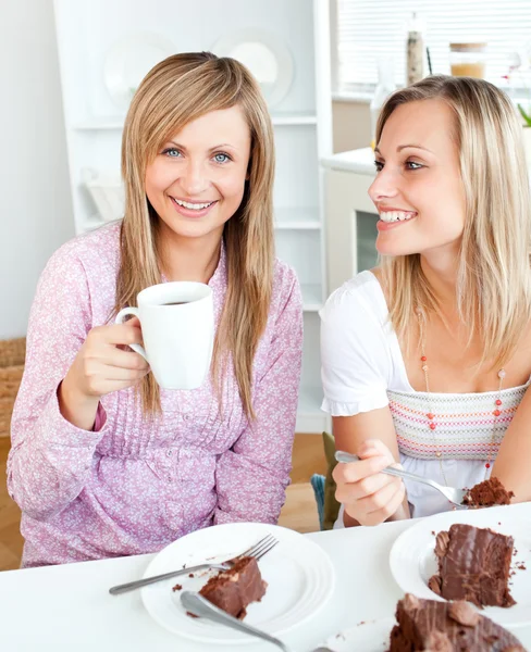 Joyful amigas comiendo un pastel de chocolate y bebiendo en th —  Fotos de Stock