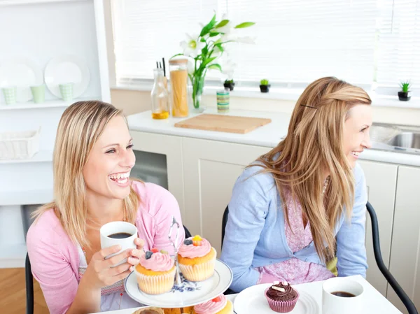 Two laughing female friends eating pastries and drinking coffee — Stock Photo, Image