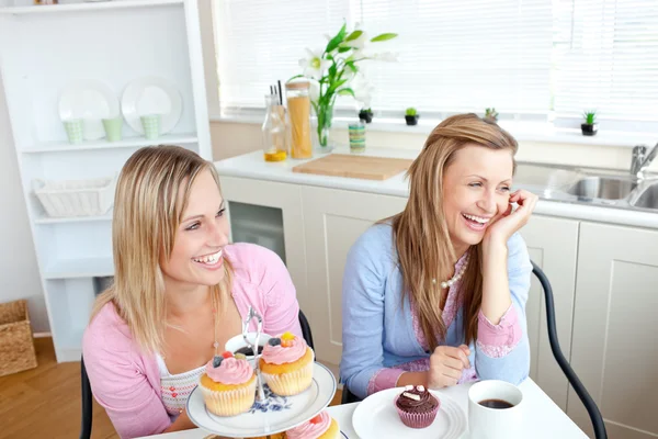 Deux amies joyeuses mangeant des pâtisseries et buvant du café — Photo