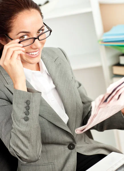 Smiling businesswoman with glasses and a newspaper sitting at he — Stock Photo, Image