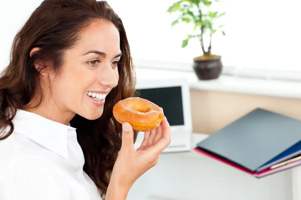 Hispanische Geschäftsfrau isst einen Donut in ihrem Büro — Stockfoto