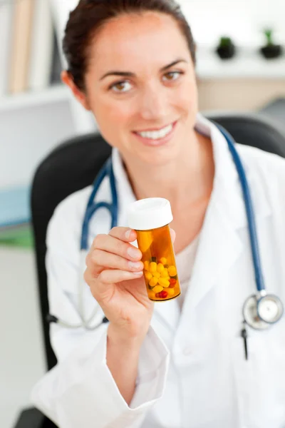 Encantado médico feminino segurando pílulas para a câmera em seu off — Fotografia de Stock