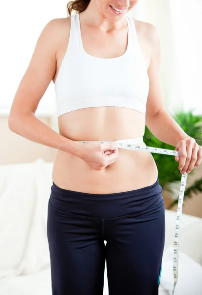 Thin hispanic woman measuring her waist with a tape in the livin — Stock Photo, Image