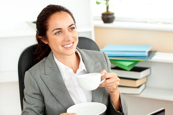 Allegra donna d'affari ispanica che beve caffè alla scrivania — Foto Stock