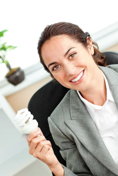 Mulher de negócios hispânica brilhante segurando uma lâmpada sentado em ele — Fotografia de Stock