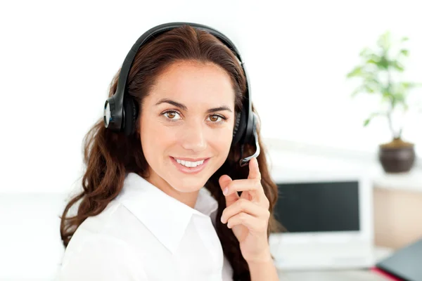 Pretty hispanic businesswoman with headset sitting at her desk — Stock Photo, Image