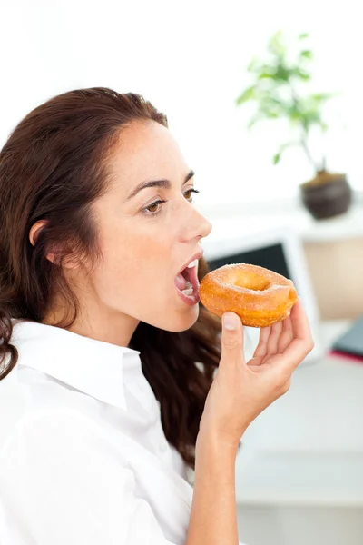 Charmosa mulher de negócios hispânica comendo um donut — Fotografia de Stock