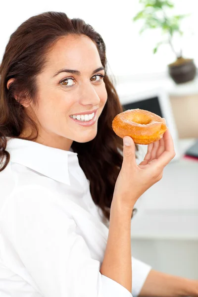 Sorrindo hispânico empresária segurando um donut — Fotografia de Stock