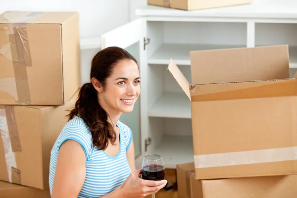 Sorridente donna ispanica bere vino tra scatole vuote — Foto Stock