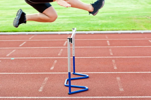 Ассертивный спортсмен прыгает над изгородью во время гонки — стоковое фото
