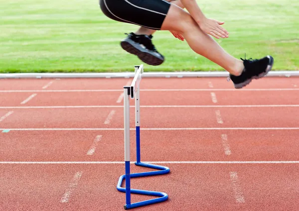 Selvsikker mannlig idrettsutøver som hopper over hekken under et løp – stockfoto