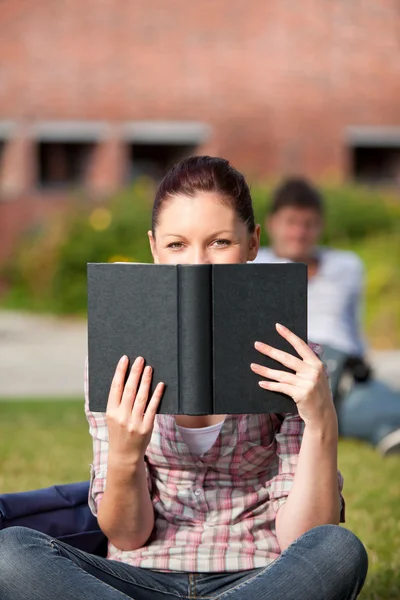 集中阅读一本书坐在草地上的女学生 — 图库照片