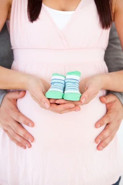 Közeli a gazdaságban a baba cipő terhes nő hasát és — Stock Fotó