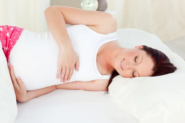 Usmívající se těhotná žena odpočívá v posteli v ložnici — Stock fotografie