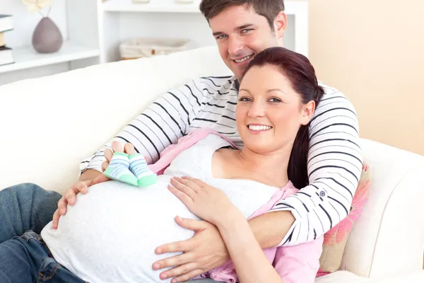 Retrato de uma mulher grávida branca segurando sapatos de bebê e de — Fotografia de Stock
