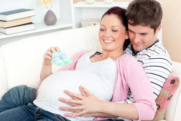 Portrait of a happy pregnant woman holding baby shoes and of her — Stock Photo, Image