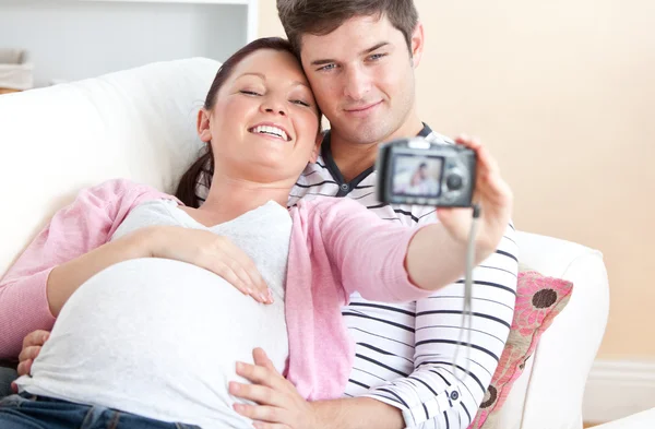 Крупный план веселой беременной женщины и ее мужа, делающего фото — стоковое фото