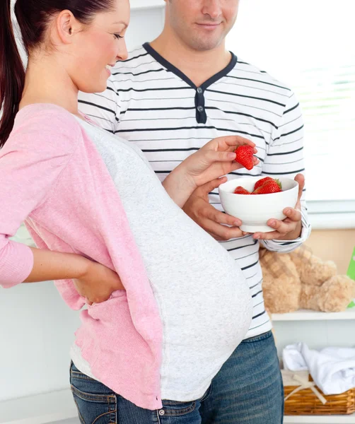 Portrait of a delighted pregnant woman eating strawberries and o — Stock Photo, Image