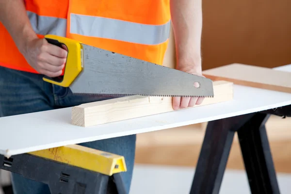 Primer plano de un trabajador masculino aserrando una tabla de madera — Foto de Stock