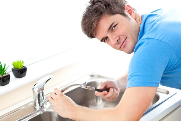Молодой человек чинит кухонную раковину — стоковое фото