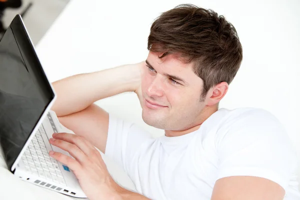 Smiling man using a laptop lying on his bed — Stock Photo, Image