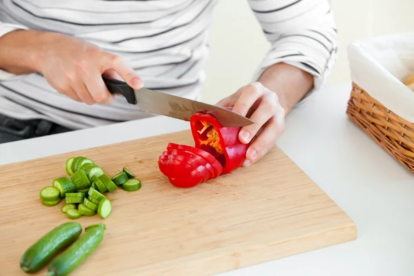 Close-up de um jovem cortando legumes na cozinha — Fotografia de Stock