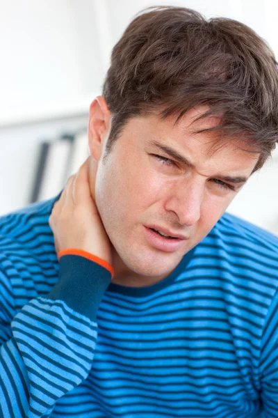 Junger kaukasischer Mann mit Nackenschmerzen im Wohnzimmer — Stockfoto
