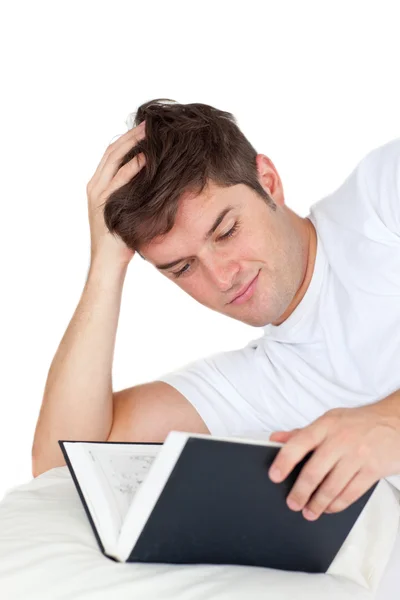 Hombre atractivo leyendo un libro acostado en su cama —  Fotos de Stock